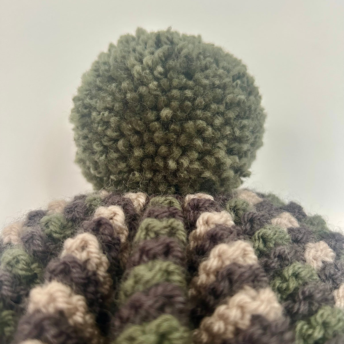 Close up of a pom pom on a hand knitted tea cosy