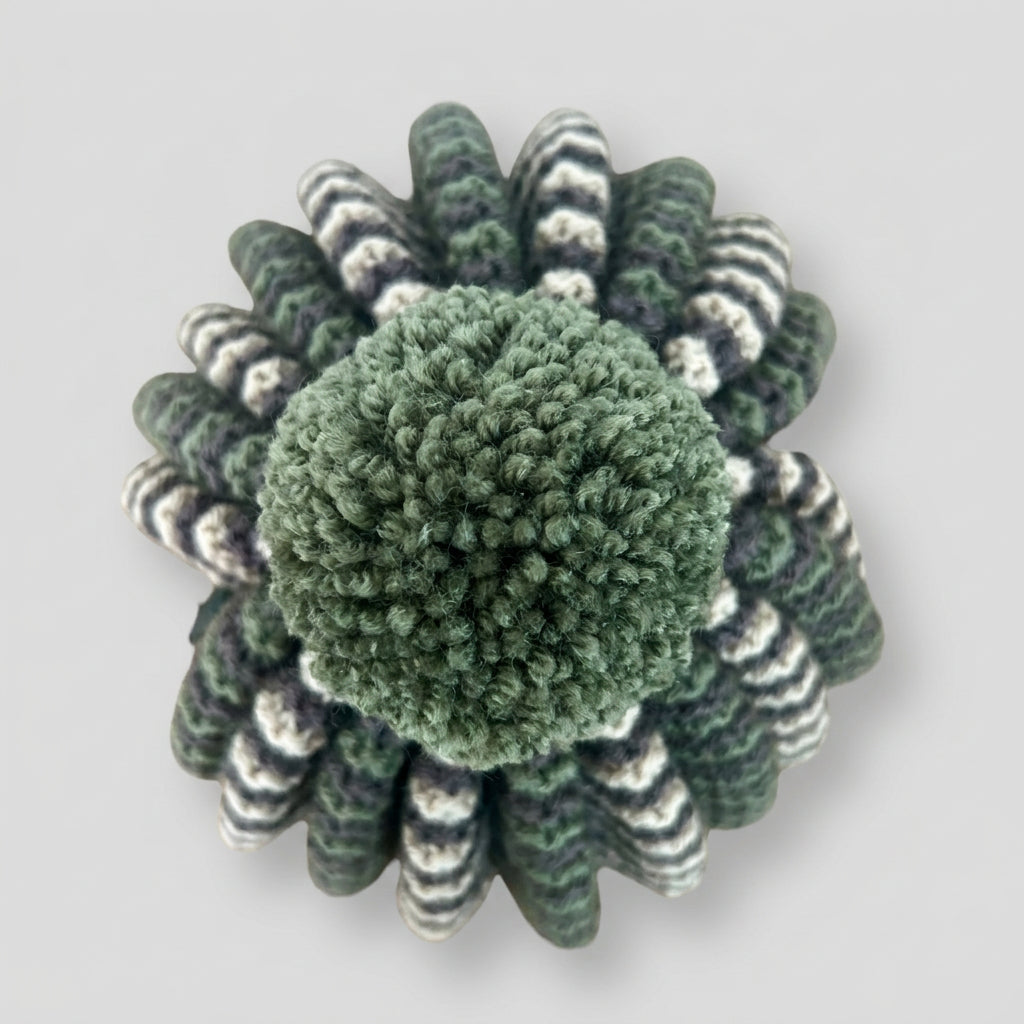 Close up of a pom pom on a hand knitted tea cosy